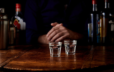 Man seated at a bar counter with two shots
