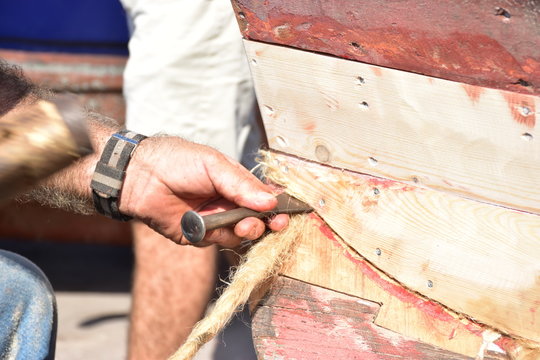  Calafataggio,  tecnica di impermeabilizzazione dello scafo in legno, eseguita dal mastro calafato. Lavoro eseguito su una barca tradizionale in legno. Sicilia, Palermo- localit&agrave; Sferracavallo