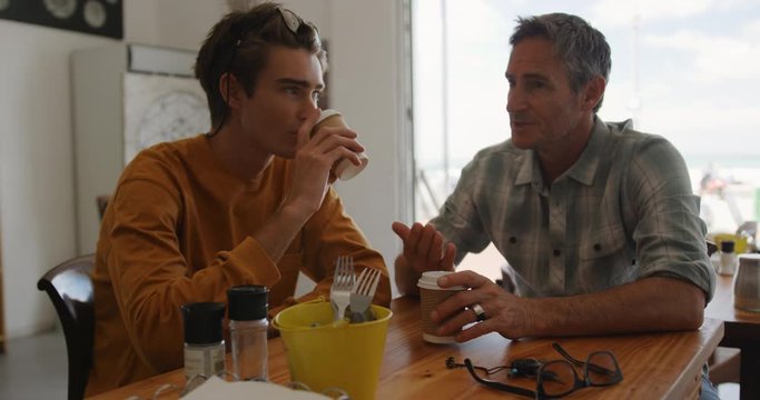 Father and young adult son in a cafe together
