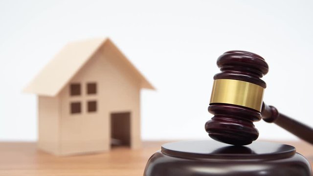 Auction or law concept. Miniature House on wooden table and judge gavel. Zoom out.