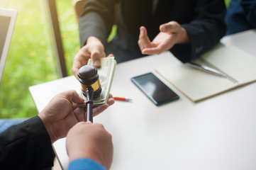 Auction collusion. The businessman holds the auction hammer and receives money from the businessman.