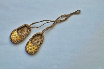 small straw sandals hang on the laces on the wall.