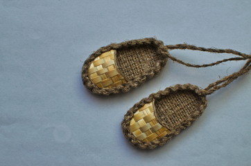 small straw sandals hang on the laces on the wall.