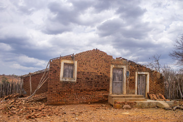 An abandoned humble house in bricks without roof with a window and two doors in the semiarid region of the state of Piauí, northeast of Brazil, drought and poor region