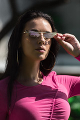 attractive woman in dress and sunglasses posing and looking at camera outside