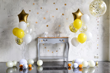 One year birthday decorations. A lot of balloons yellow and silver colors.
