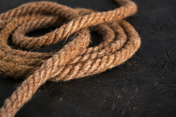 Coiled roll of jute rope on abstract background.