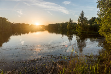 summer riverscape with blue sky, clouds, sunset and water reflections