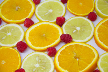 slices of orange and lemon and raspberries on white. Looks like a background