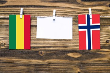 Hanging flags of Bolivia and Norway attached to rope with clothes pins with copy space on white note paper on wooden background.Diplomatic relations between countries.