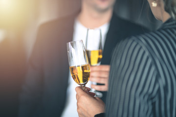 People having a conversation while holding a glass of champagne indoors.