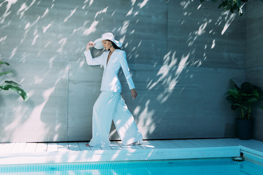 Attractive Woman In White Suit And Hat Walking Outside