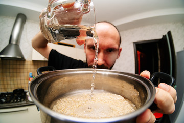 man pours water into a pot in the kitchen