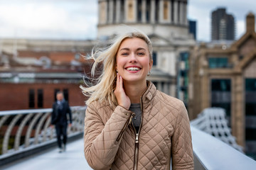 Portrait einer attraktiven, blonden Frau in herbstlicher Kleidung vor der St. Pauls Kirche in London