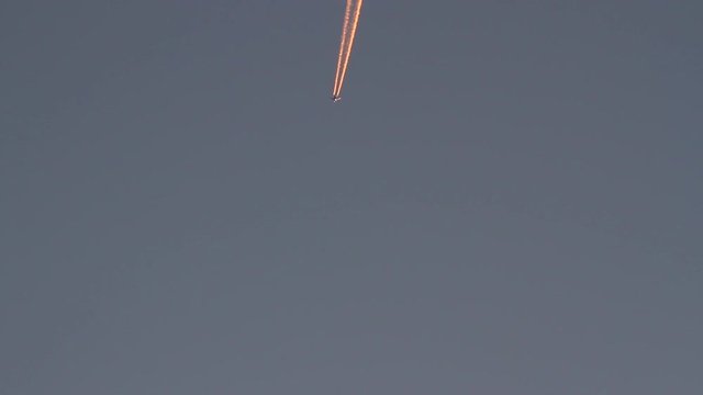 Avi&oacute;n en el cielo cruzando  la pantalla y dejando rastro o estela con reflejo de sol de atardecer