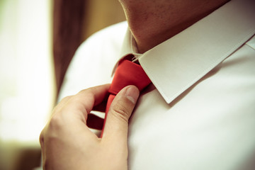 male hands straighten red tie close-up and toned