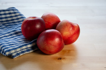 Four peaches on the table with tablecloth.