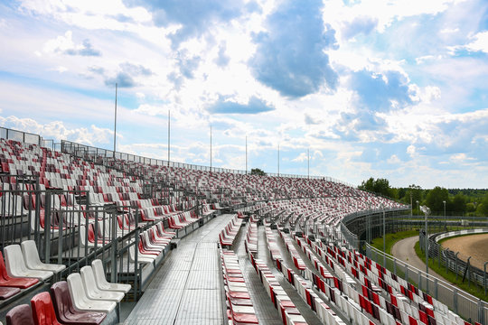 empty tribune on the race track in the open. red and white seats in the stands. background of tribune without people. free seats on the arena.