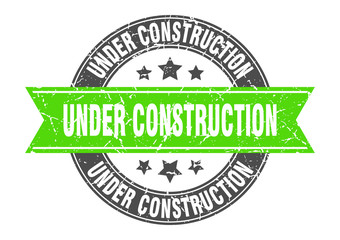under construction round stamp with green ribbon. under construction