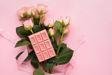 Chocolate pink handmade tile and rose flowers on a pink background. Minimalism holiday concept. Top view flat layout