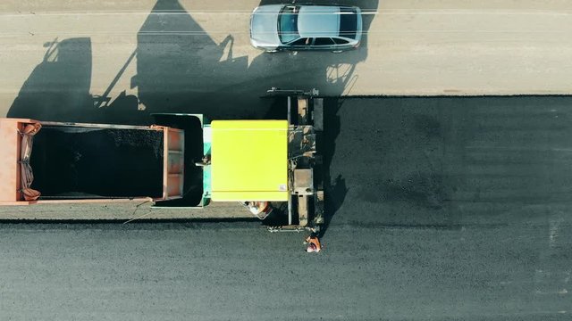 Asphalt laying machine works. Working machines and people on a road laying asphalt.