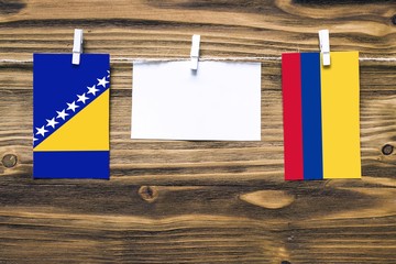 Hanging flags of Bosnia Herzegovina and Colombia attached to rope with clothes pins with copy space...