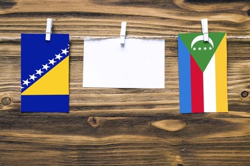 Hanging flags of Bosnia Herzegovina and Comoros attached to rope with clothes pins with copy space...