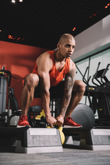 Fototapeta na wymiar young african american sportsman lifting weight in gym