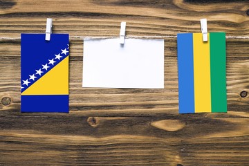 Hanging flags of Bosnia Herzegovina and Gabon attached to rope with clothes pins with copy space on...