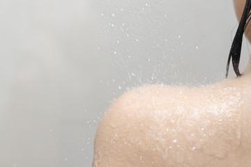 Woman taking a shower Turn on the shower and the water flows over the shoulders. Have copy space.