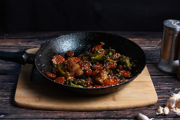 A hot pan with fried vegetables, broccoli, cauliflower, carrots.
