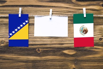 Hanging flags of Bosnia Herzegovina and Mexico attached to rope with clothes pins with copy space...