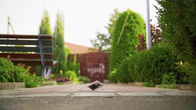 Mobile phone falls and breaks on the concrete ground in slow motion