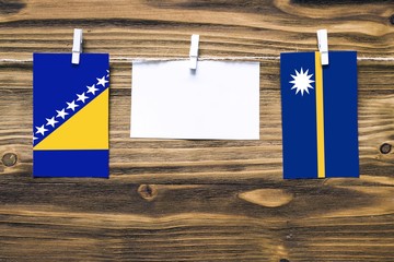 Hanging flags of Bosnia Herzegovina and Nauru attached to rope with clothes pins with copy space on...
