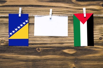 Hanging flags of Bosnia Herzegovina and Palestine attached to rope with clothes pins with copy...