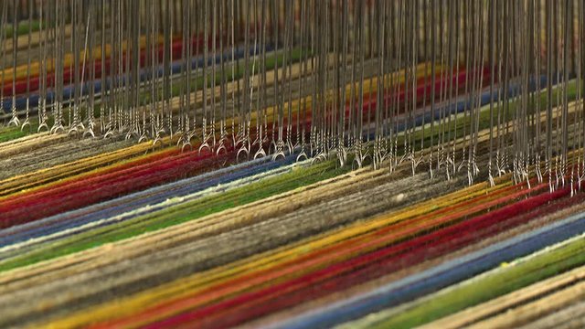 Close up of a colorful variety of rich, vibrant threads on a loom ready to be made into cloth