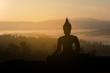 Silhouette Buddha on golden sunset background.