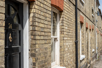 Detailed view of well-maintained, terraced houses seen in an English town. Detail of a black painted front door and sash windows is evident.