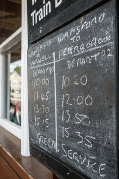 Shallow focus view of a chalk type train timetable seen on an old railway station within the UK, now used for heritage days