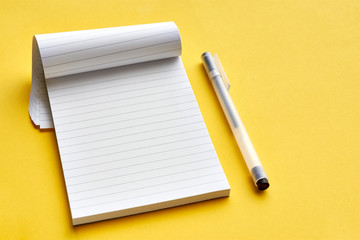 Top view of blank open notebook page with lines and transparent minimalistic fineliner pen on yellow background with copy space. For use as mock up.     - obrazy, fototapety, plakaty