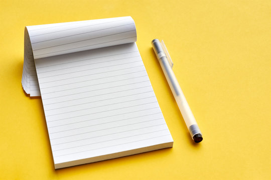 Top view of blank open notebook page with lines and transparent minimalistic fineliner pen on yellow background with copy space. For use as mock up.    