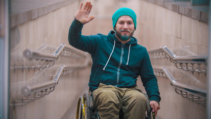 Disabled man in wheelchair waving with his hand
