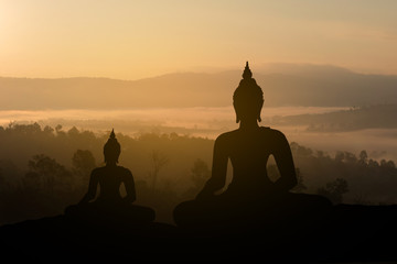 Silhouette Buddha on golden sunset background.
