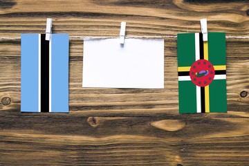 Hanging flags of Botswana and Dominica attached to rope with clothes pins with copy space on white...