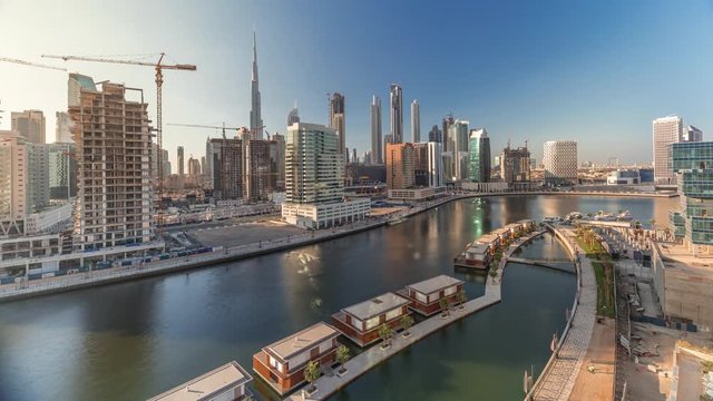 Small and luxury houses and skyscrapers near canal with clouds in the blue sky before sunset aerial timelapse in Business Bay, Dubai, United Arab Emirates