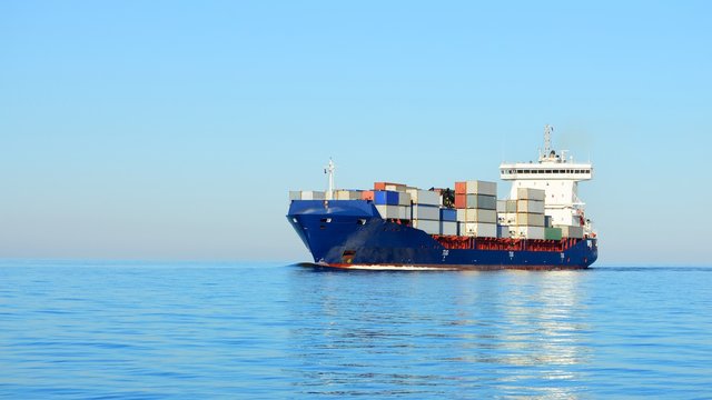 Large cargo container ship sailing in a bright sunny day. Riga, Latvia