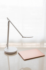 Fototapeta na wymiar Modern rose gold laptop and white lamp on white desk