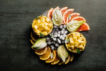 Fruit platter. Platter of grapefruit, pineapples, grapes and apples on a dark background