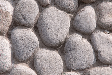 Natural background. Texture of a rough gray stone surface. Gray round cobblestone knitted with cement. Close-up, horizontal, cropped shot. The concept of natural beauty and construction.