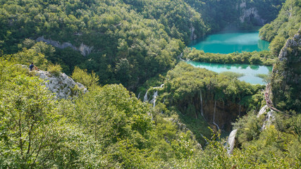 A visitor to the Plitvice Lakes Park admires the cascade of lakes and noisy waterfalls from a high cliff